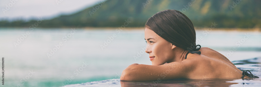 Luxury vacation woman relaxing in infinity swimming pool on summer travel at beach resort. Asian girl tourist on wellness spa relaxation outside in nature landscape banner panorama. - obrazy, fototapety, plakaty 