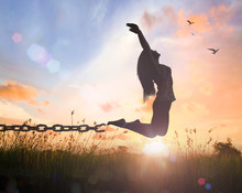 Individual Human Right Day Concept: Silhouette Of A Woman Jumping And Broken Chains At Orange Meadow Autumn Sunset  With Her Hands Raised