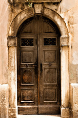 Wall Mural - Ancient wooden door with lock in old stone wall. Toned photo.