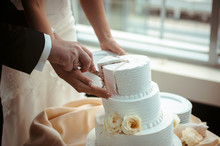 A Bride And A Groom Is Cutting Their Wedding Cake. Beautiful Cake. Nicel Light. Wedding Concept