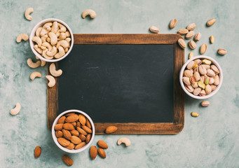 Varieties of nuts: cashew, pistachio, almond. Health concept. Chalkboard with copy space top view