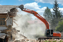 Industrial Excavator Working At The Demolition Of An Old Residential Building
