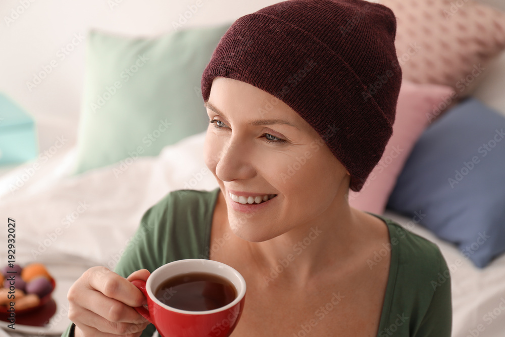 Young woman with cancer drinking tea indoors