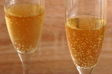 Two glasses with champagne. Bubbles in the glasses create a holiday atmosphere. Light wooden background. Close-up. Macro photography.