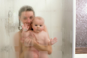 Mother and baby boy in shower, drops of water