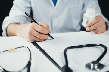 the doctor writes the prescription and keep the pills on a white background in a Bathrobe in the hospital