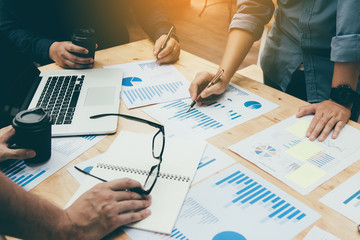 Co-working space office with group start-up analysis to data paper chart on desk.