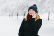 © Romvy - Young caucasian blonde girl in black coat and red knitted scarf walks in winter park with smartphone