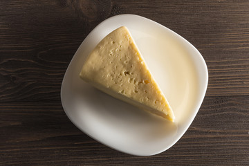  Cheese on a white plate on a dark wooden background