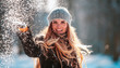 © leszekglasner - Smiling young woman throwing snow in the air looking at camera