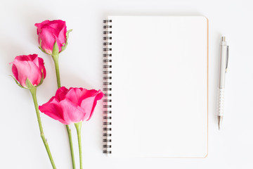 Wall Mural - blank notebook with pink roses and pen on white background,flat lay photo of a notebook for your mes