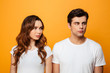 © Drobot Dean - Photo of displeased boyfriend and girlfriend in white t-shirts being in fight while posing on camera with offended look, isolated over yellow background