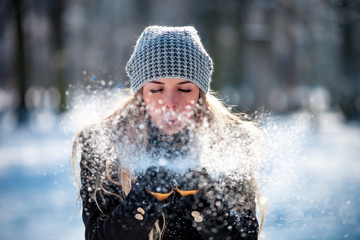 Winter woman blowing snow outdoor, flying snowflakes