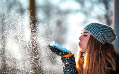 Wall Mural - Winter woman blowing snow outdoor at sunny day, flying snowflakes