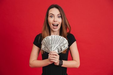 Wall Mural - Portrait of an excited girl holding bunch of money banknotes