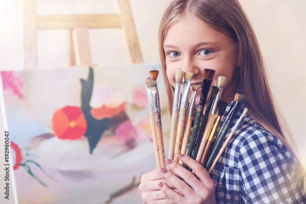 SEt of a real artist. Positive girl sitting at her easel and holding ...