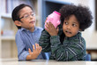 © Nattanon - Kids Playing With a Pink Saving Pig Jar in the Library. Boys has listening to money Accumulated dividend success. Setup studio shooting.