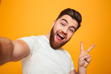 Wall Mural - Portrait of a cheerful bearded man showing peace gesture