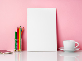 Wall Mural - Blank white frame and crayon in jar, cup of coffee r tea on a white table against the pink wall with copy space