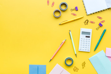 Wall Mural - Scattered stationery on student's desk. Yellow background top view copy space
