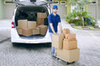 © Creativa Images - Young Delivery Man In Front Van pushing trolley