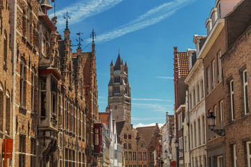 Wall Mural - Tower of the Cathedral of Saint Salvator in Bruges, Belgium. Typical street with the medieval Flemish architecture and red brick houses.