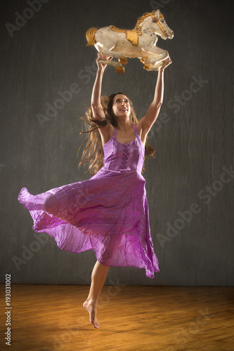 Fotografie, Obraz Young woman in purple dress dancing with antique carousel horse.