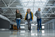 © Yakobchuk Olena - Low angle portrait of three ladies with luggage running across terminal hall. They having joyful facial expressions