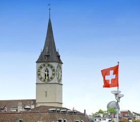 Canvas Print - Clock tower of the St. Peter Church and Swiss Flag on the facade building in Zurich, Switzerland