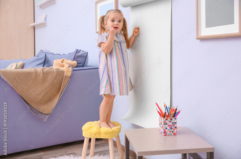 Little cute girl drawing on paper roller indoors