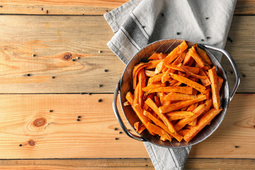 Wall Mural - Pan with sweet potato fries on wooden table