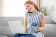 © Africa Studio - Young woman with credit card talking on phone. Online shopping