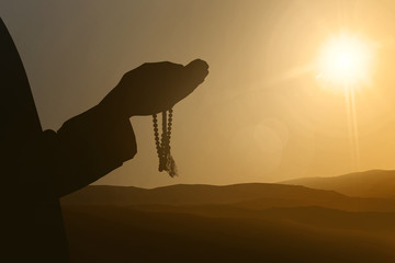 Silhouettes of muslim people praying to god