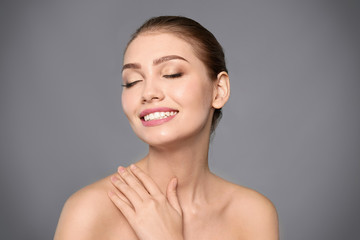 Poster - Portrait of beautiful young woman with clear skin on grey background