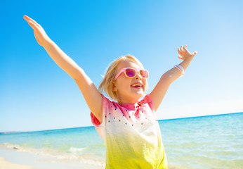 Wall Mural - happy trendy child in colorful shirt on seacoast rejoicing