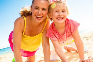 Wall Mural - happy trendy mother and child in colorful clothes on beach