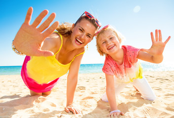 Wall Mural - smiling modern mother and child on seashore showing palms