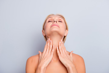 portrait of pretty, charming, attractive woman enjoying her perfect skin holding two hands on neck, 
