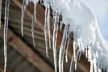 Icicles And Snow Overhanging A Roof