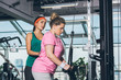 © LIGHTFIELD STUDIOS - trainer helping to overweight woman while she training on training apparatus