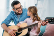 © LIGHTFIELD STUDIOS - father teaching daughter play guitar at home