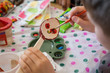 Child painting flowers on a wooden spoon using acrylic paints 