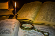 Old Book And Magnifier Glass Under The Light Candle