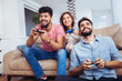 © Mediteraneo - Group of young friends play video games together at home.