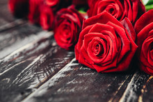 Beautiful Scarlet Roses On A Black Wooden Background