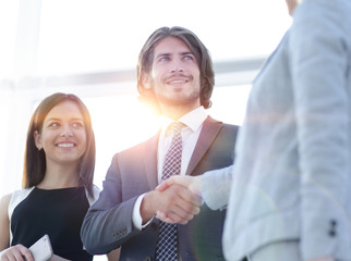 Wall Mural - Businesspeople  shaking hands against room with large window loo