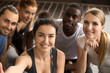© fizkes - Young smiling sporty multiracial friends taking group selfie photo holding looking at camera, happy healthy diverse fit people making self-portrait after working out together in gym, view from camera