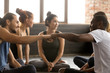 © fizkes - Smiling sporty fit african american and caucasian men fist bumping at group training meeting in gym studio, two diverse friends greeting or supporting team motivation for sport yoga teamwork concept
