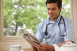© Erickson Stock - Portrait of doctor taking a break and reading the paper.