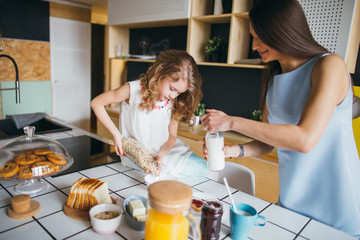 Mother and daughter making breakfast together at home 